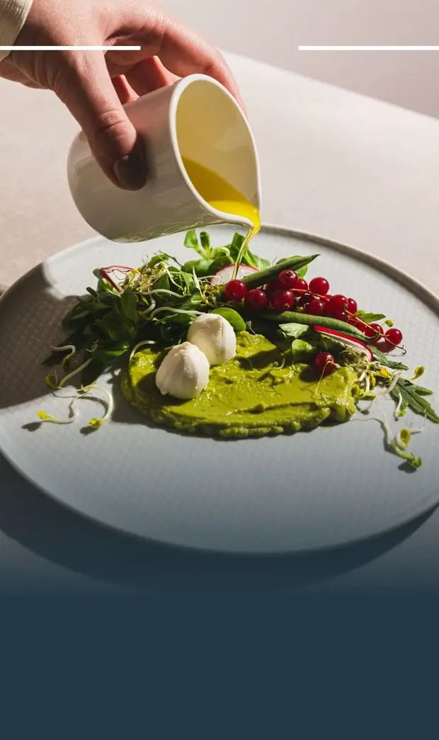 Plato emplatado de alta cocina al que se le añade un aceite desde una jarra.
