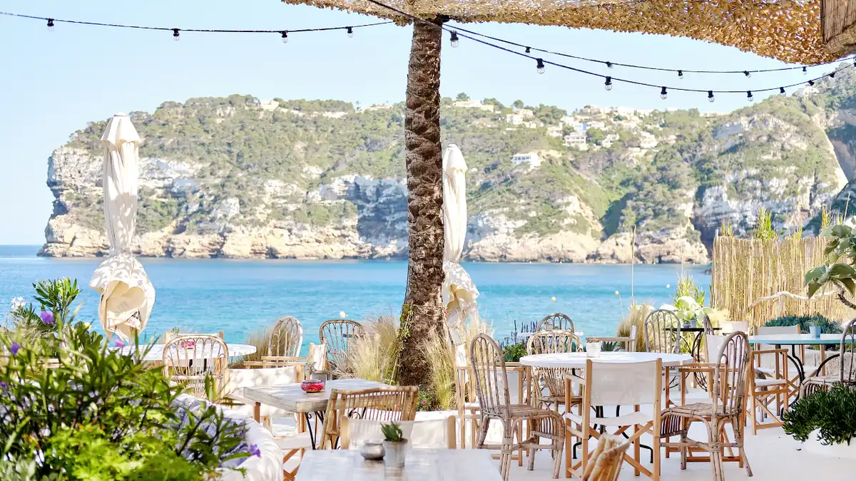 Terraza de un restaurante junto al mar, montada y lista para el servicio.