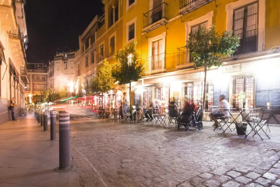 Calle de una ciudad española con terrazas de bares llenas por la noche.